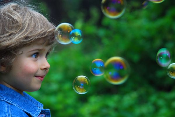Curious four year old child playing with bubbles